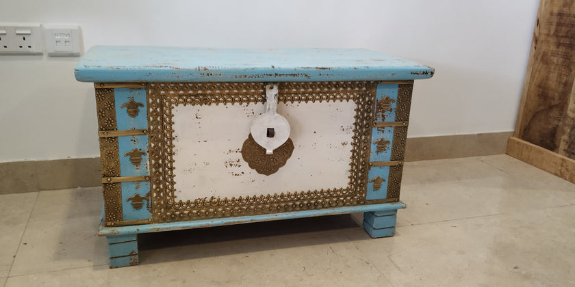 Decorative wooden chest with blue accents on a plain floor.